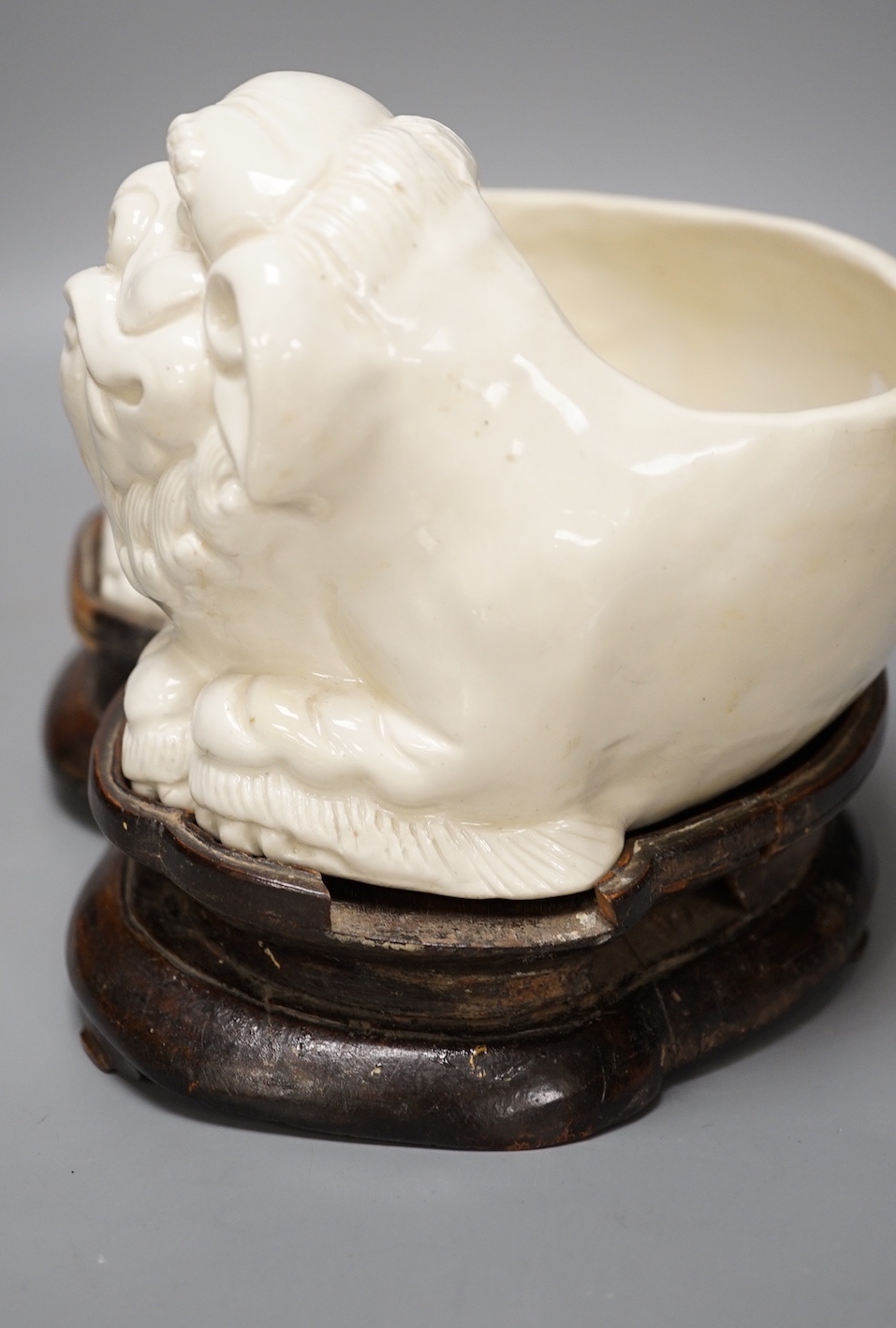 A Chinese cream glazed lion’dog planter on hardwood stand, 21cm